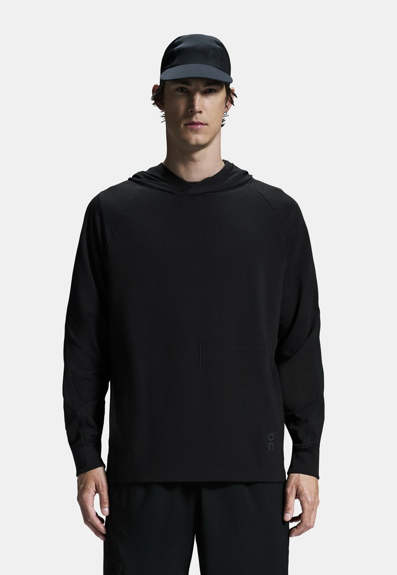 Mustat pitkähihaiset hupparit, jotka on valmistettu sileästä ja kevyestä kankaasta, joissa on kengurulaukku ja resorit, yhdistettynä samanlaiseen mustaan lippikseen.