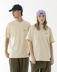 Unisex kreemjad T-särgid lühikeste varrukatega, vasakus rinnas on tikandiga logo, mida on kombineeritud oliivroheliste pükstega ja tekstuuriga beanie'ga.