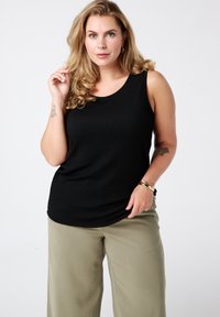 Zwart geribd tanktop met een ronde halslijn, gecombineerd met licht olijfgroene brede broekspijpen. Glad textuur en aansluitend ontwerp.