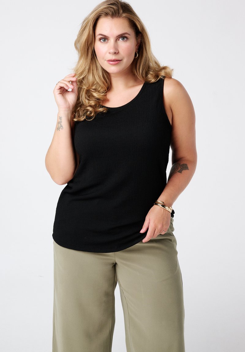 Zwart geribd tanktop met een ronde halslijn, gecombineerd met licht olijfgroene brede broekspijpen. Glad textuur en aansluitend ontwerp.