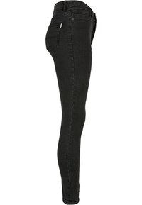 Fekete farmer skinny nadrág sima textúrával, magas derékkal és testhez simuló kialakítással. Elöl és hátul zsebekkel, minimális varrással.