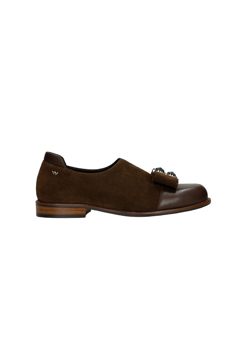 Chaussure en daim brun avec un bout en cuir lisse brun, ornée d'un nœud décoratif et d'accents métalliques. Talon en bois bas et forme arrondie.
