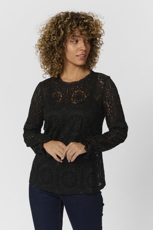 Black lace top with long sleeves, featuring a floral pattern and scalloped neckline. The fabric has a delicate, woven texture.