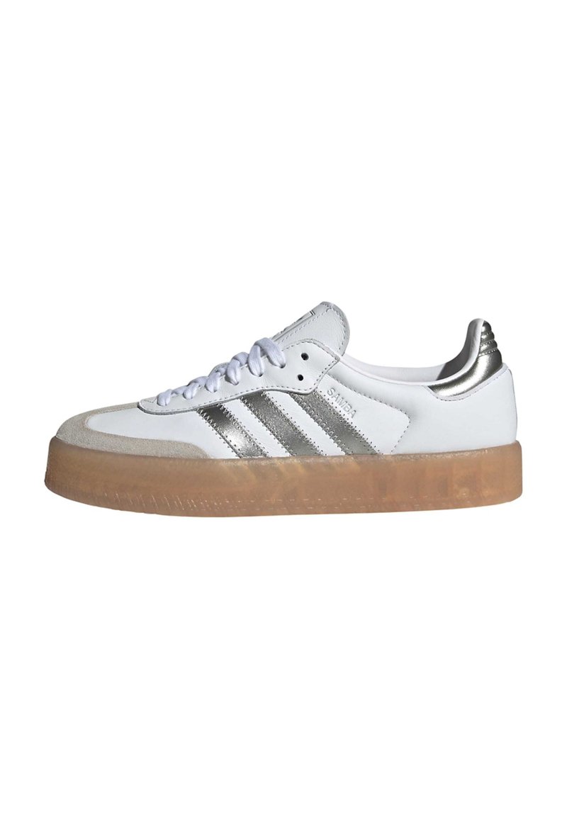 Białe sneakersy z srebrnymi trzema paskami, brązową gumową podeszwą oraz białą teksturowaną cholewką z okrągłym czubkiem i sznurowanym zapięciem.