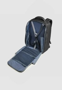 Zaino nero con texture, aperto, che mostra l'interno grigio con spallacci regolabili, molteplici tasche e scomparti con cerniera per l'organizzazione.