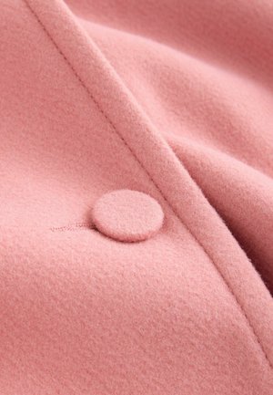 Rosa Wollstoff mit weicher Textur, ausgestattet mit einem runden, mit Stoff bezogenen Knopf und einer sauberen, maßgeschneiderten Naht.