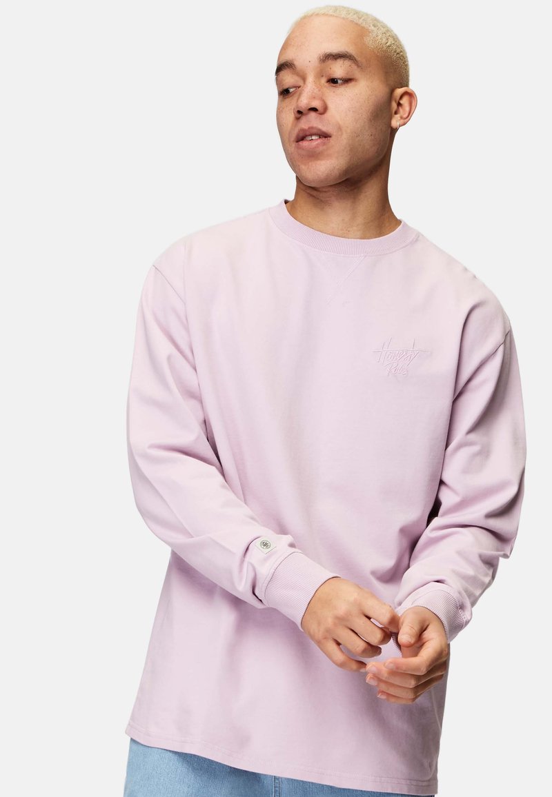 Ljusrosa långärmad sweatshirt i mjuk bomull. Har ribbade ärmslut och en liten tonad logotyp på bröstet. Avslappnad passform, rund halsringning.