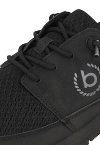 Svart sneaker med mesh-tyg och läderdetaljer, runda snörningar och en logotyp-emblem. Designen är lågprofil med en texturerad yta.
