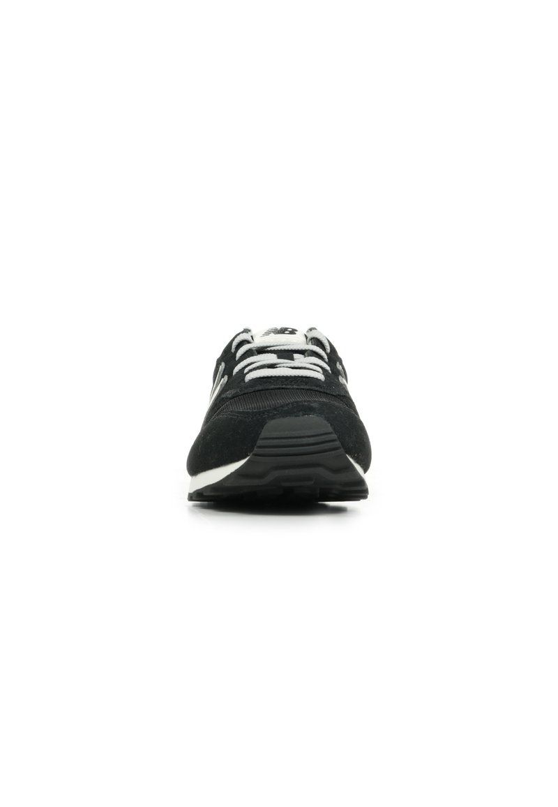 Zapatilla deportiva negra con parte superior de ante, cordones blancos y suela de goma. Presenta un diseño suave y una ligera elevación del talón.