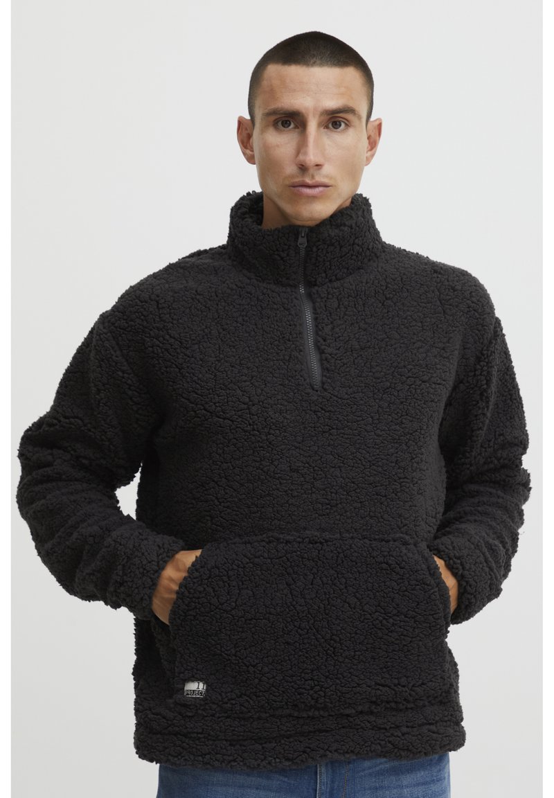 Sort fleece pullover med halvlukket hals, tekstureret stof og kengurupocket. Har et lille mærke i kanten.