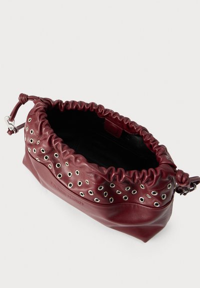 Μικρή δερμάτινη τσάντα ώμου σε μαροon χρώμα, με συγκεντρωμένο πάνω μέρος και ασημένιες λεπτομέρειες με οπές κατά μήκος της άνω άκρης, γωνιακή λήψη που δείχνει το ανοιχτό εσωτερικό.