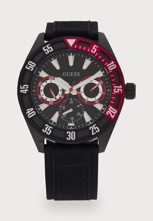 Montre chronographe noire avec un bracelet noir, accents rouges audacieux, grands index horaires blancs et trois sous-cadrans. Caractérisée par une lunette tournante.