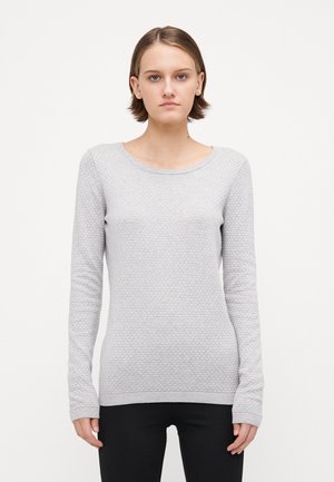Vaaleanharmaa pitkähihainen neule, jossa on tekstuuri ja ribbauskaulus. Slim fit -leikkaus ja tiukat hihat, yhdistetty mustiin housuihin.