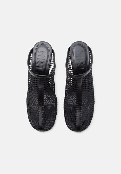 Ζευγάρι μαύρα ανοιχτά παπούτσια χωρίς πίσω μέρος με επάνω μέρος από δίχτυ και δερμάτινες λεπτομέρειες, σε λευκό φόντο, φωτογραφημένα από ψηλά.