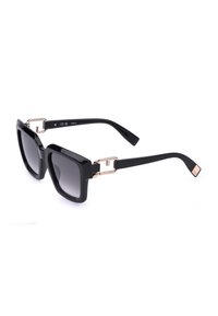 Lunettes de soleil carrées noires oversize avec verres sombres dégradés et accents en métal doré aux charnières sur les branches.
