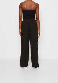 Černý bezramínkový top spárovaný s volnými cargo kalhotami. Kalhoty mají boční kapsy a uvolněný střih, vyrobené z lehkého materiálu.