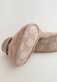 Chalecos de casa en forma de oso rosa, que presentan un material suave y esponjoso, y una suela texturizada con patrones de oso. Tienen una forma redondeada y un diseño acolchado.