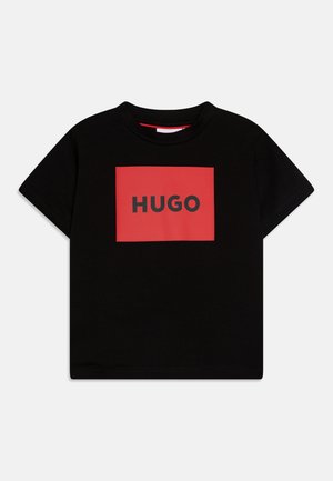 Zwarte katoenen t-shirt met een rood rechthoekig logo met "HUGO" in vetgedrukte zwarte letters. Korte mouwen en ronde hals.