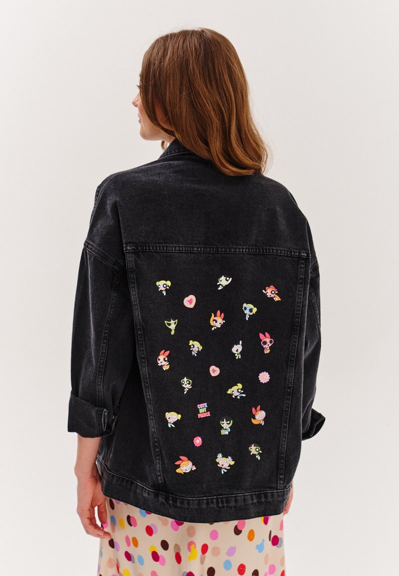 Czarna kurtka dżinsowa z kolorowymi naszywkami postaci z kreskówek z tyłu, w tym serca i kwiaty. Luźny krój z podwiniętymi rękawami.