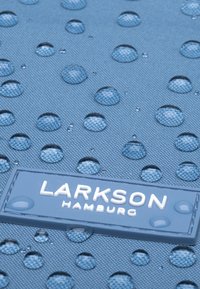 Kék, texturált anyag vízcseppekkel, az alsó részen egy fehér téglalap alakú logóval: "LARKSON HAMBURG".