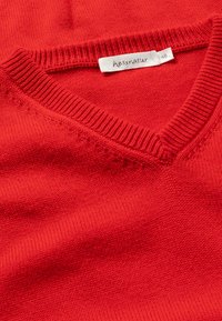 Roter Pullover mit V-Ausschnitt, geripptem Kragen und feiner Strickstruktur. Das Etikett zeigt den Markennamen "hessnatur" und die Größe "48."