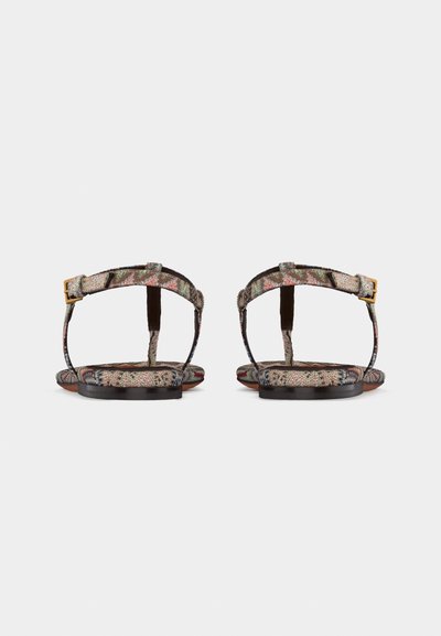 Οπίσθια όψη μοτίβων επίπεδων σανδαλιών με λουριά στον αστράγαλο και χρυσές πόρπες σε απλό λευκό φόντο.