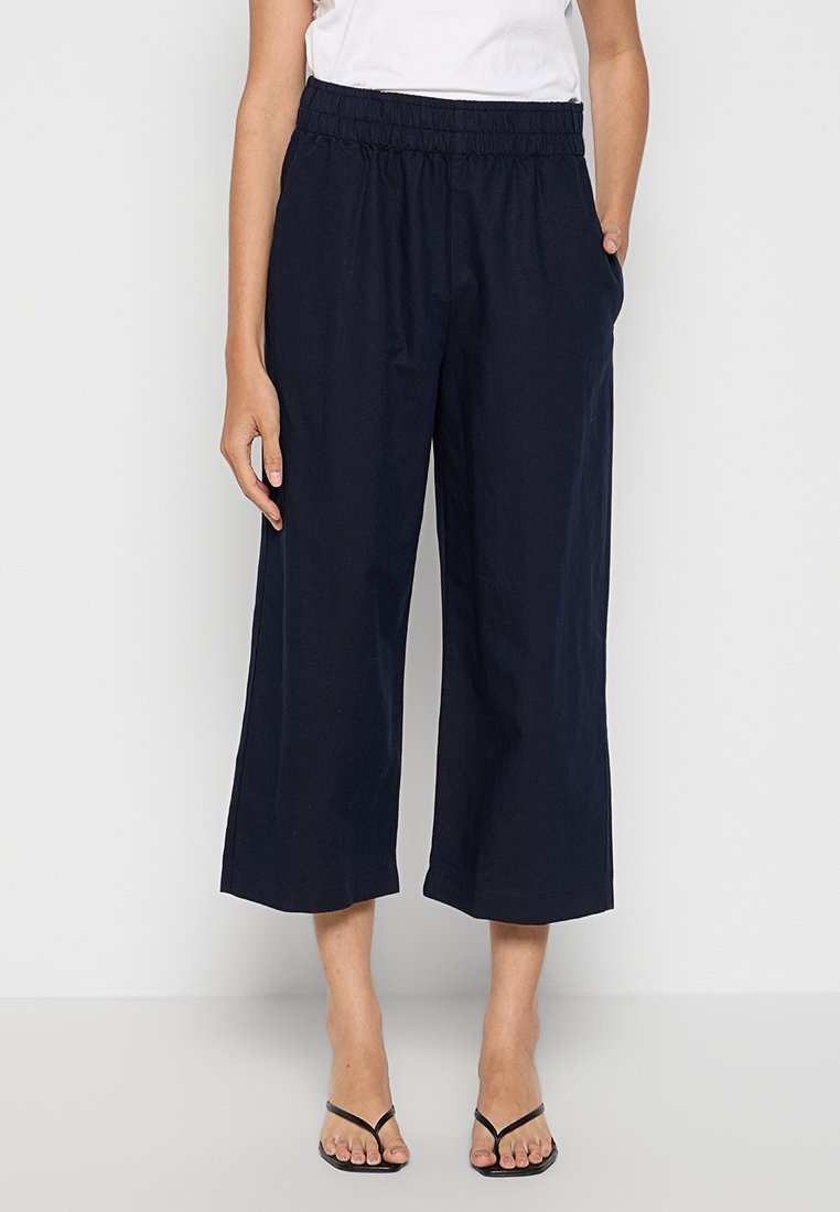 Marineblaue, weite Hosen aus leichtem Baumwollstoff, mit einem elastischen Bund und seitlichen Taschen, in einer knöchellangen, geschnittenen Ausführung.