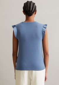 Blaues ärmelloses Oberteil mit Rüschendetails an den Schultern, aus einem weichen Stoff gefertigt, zeigt eine figurbetonte Silhouette und einen sauberen Saum.