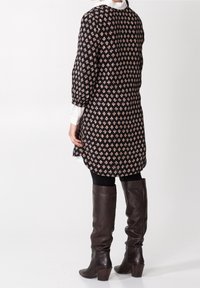 Czarna sukienka w wzory z bufkami, ozdobiona kwiatowym motywem w beżu i rudym. W zestawie z brązowymi skórzanymi kozaki do kolan.