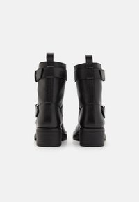 Black leather ankle boots with textured finish, two adjustable straps, and a stacked heel, featuring a rounded toe and pull tabs.