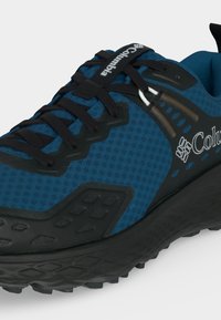Baskets trail Columbia bleu et noir avec empeigne en mesh, lacets noirs, languette brandée et semelle extérieure en caoutchouc noir texturé.