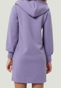 Robe à capuche violette avec manches longues bouffantes et une capuche. Confectionnée en tissu doux, elle présente une coupe droite et des poignets côtelés.