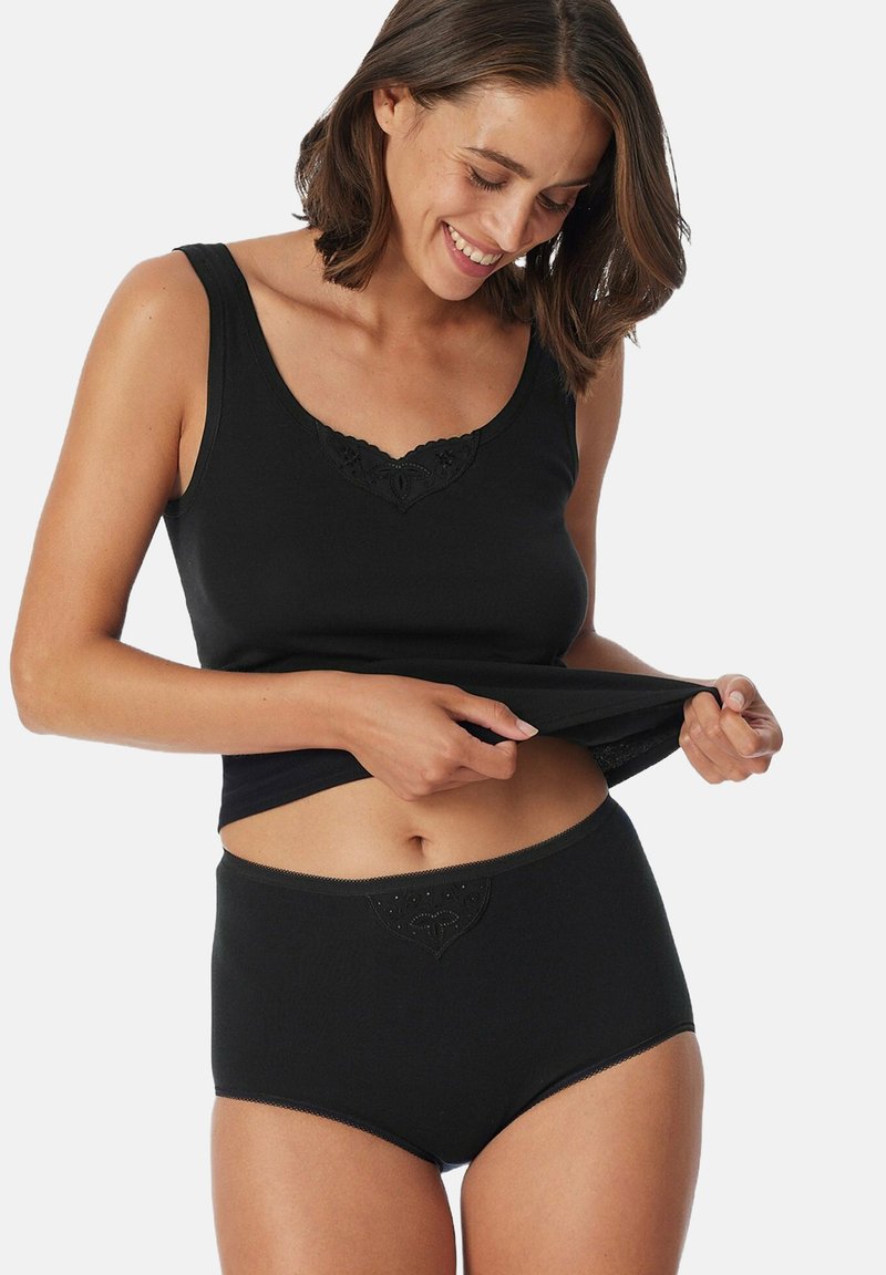 Schwarzes Tanktop mit Spitzenbesatz am Ausschnitt, kombiniert mit hochgeschnittenen schwarzen Unterhosen, die ein dekoratives Detail am Bund aufweisen.