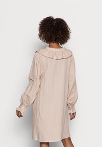 Vestido de lino rosa claro con cuello con volantes, mangas largas abullonadas con puños de botones y silueta en A, tejido texturizado.