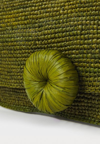 Grønn vevd bag med en teksturert overflate og en rund, bladformet knappelåsing. Materialet ser naturlig og organisk ut i design.