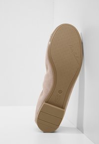Semelle d'une chaussure ballerine beige avec grip texturé, taille 37, marque "Pretty Ballerinas", reposant contre un mur et un sol blancs.