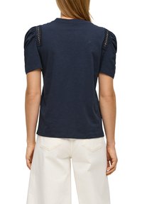 Navy blauwe katoen t-shirt met pofmouwen en kantdetail op de schouders; heeft een ontspannen pasvorm en ronde halslijn. Achteraanzicht weergegeven.