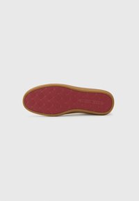 Rubber shoe sole with a textured red bottom featuring a diamond pattern, bordered by a tan edge, providing traction and durability.