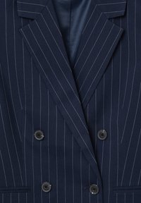 Blazer doppiopetto a righe navy con linee bianche a contrasto, revers a punta, due bottoni neri e fodera interna liscia.