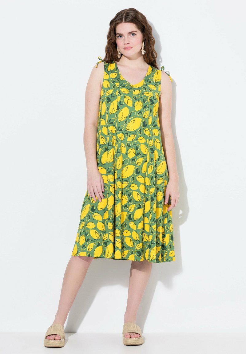 Robe florale jaune et verte avec un motif de citron, sans manches, avec des liens aux épaules et un ourlet évasé. Tissu doux et respirant.