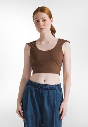 Bruine cropped tanktop met een ronde halslijn en korte mouwen, gecombineerd met een losse pasvorm blauwe denimbroek met een elastische tailleband.
