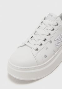 Adidași platformă albi cu un exterior din piele netedă, având ochiuri din metal argintiu, logo brodat și strasuri decorative.
