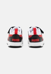 Baskets noires et rouges avec une tige en cuir lisse, doublure en maille blanche, sangle Velcro et logo "PUMA" bien en vue sur le talon.