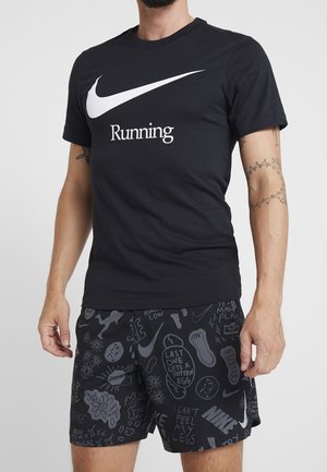 Czarny bawełniany T-shirt z białym logo Nike swoosh oraz napisem "Running", w połączeniu z czarnymi szortami z graficznym wzorem i akcentami tekstowymi.