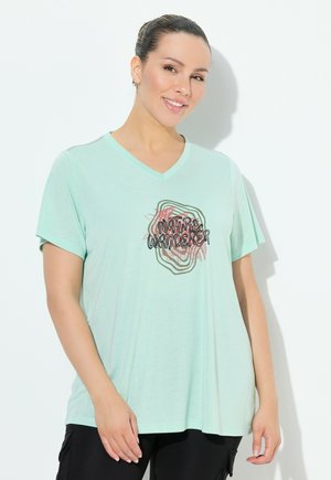 Camiseta V de color verde menta claro, hecha de una tela suave, con un gráfico en negro y rojo que dice "explorador de la naturaleza" en el frente.