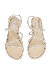 Złote i beżowe sandały z krzyżującymi się błyszczącymi paskami, płaską podeszwą i gładką teksturą. Regulowany pasek wokół kostki z złotą klamrą.