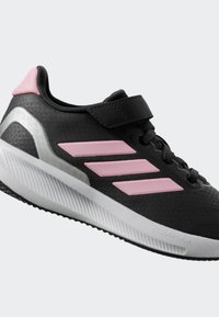 Black athletic shoe with pink accents, mesh upper, padded collar, hook-and-loop strap, and textured white sole with gray detailing.