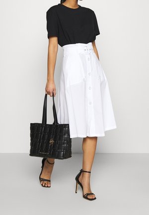 Black short-sleeve t-shirt, white button-down A-line skirt, black woven tote bag, and black strappy high-heeled sandals.