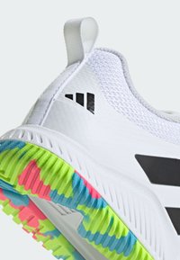 White athletic shoe with mesh upper, black accents, and a multicolored, textured rubber sole featuring green, pink, and blue patterns.