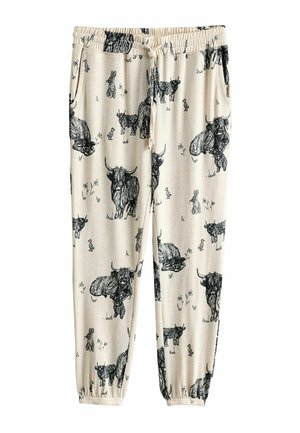 Joggers en coton beige clair avec illustrations animales noires, comprenant des vaches et des lapins, avec une taille élastique et des chevilles resserrées.